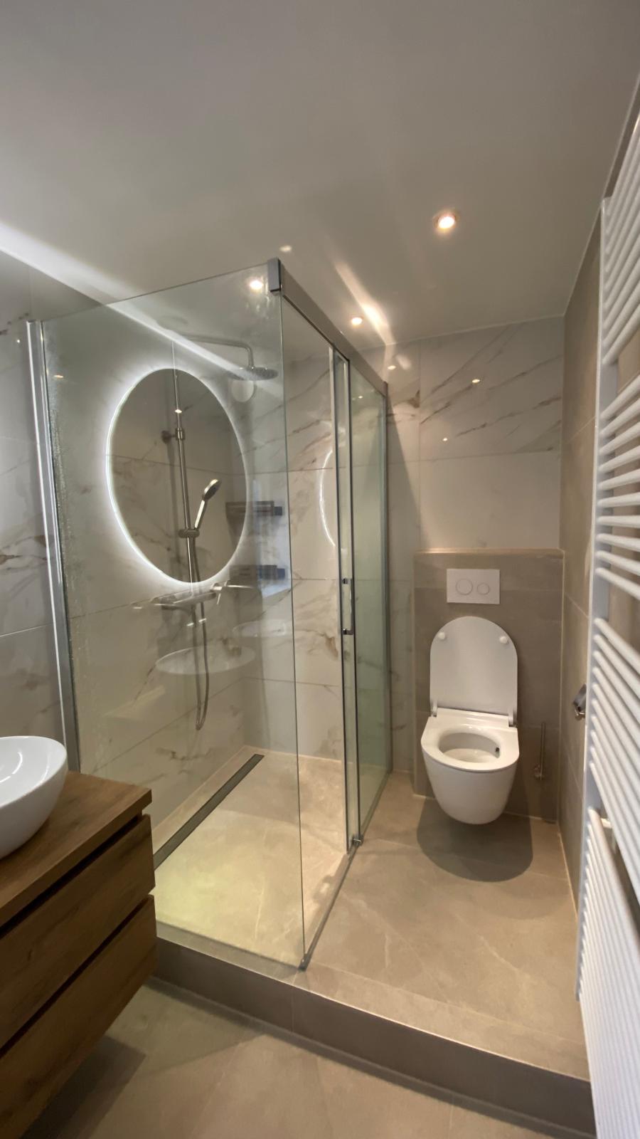 Badkamer met ligbad, twee waskommen en een glazen douchecabine.